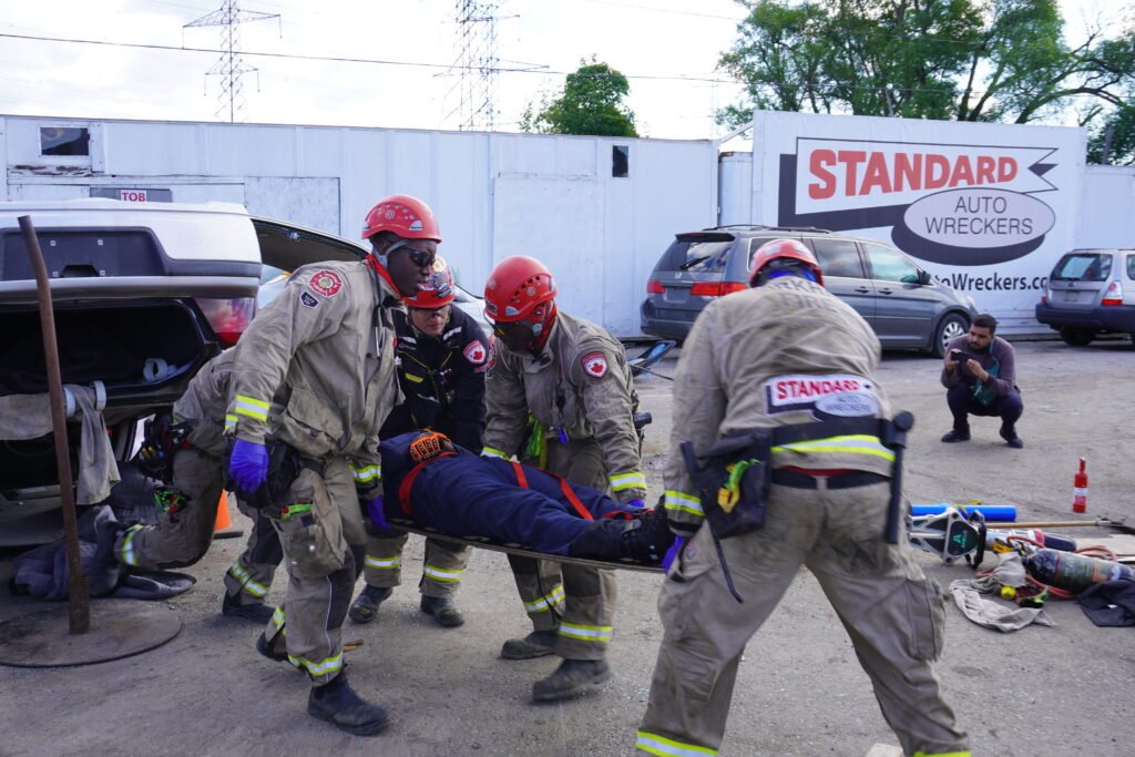 Markham Auto-Extrication Team training at Standard Auto Wreckers yard, using specialized tools on a donated scrap vehicle for rescue simulation
